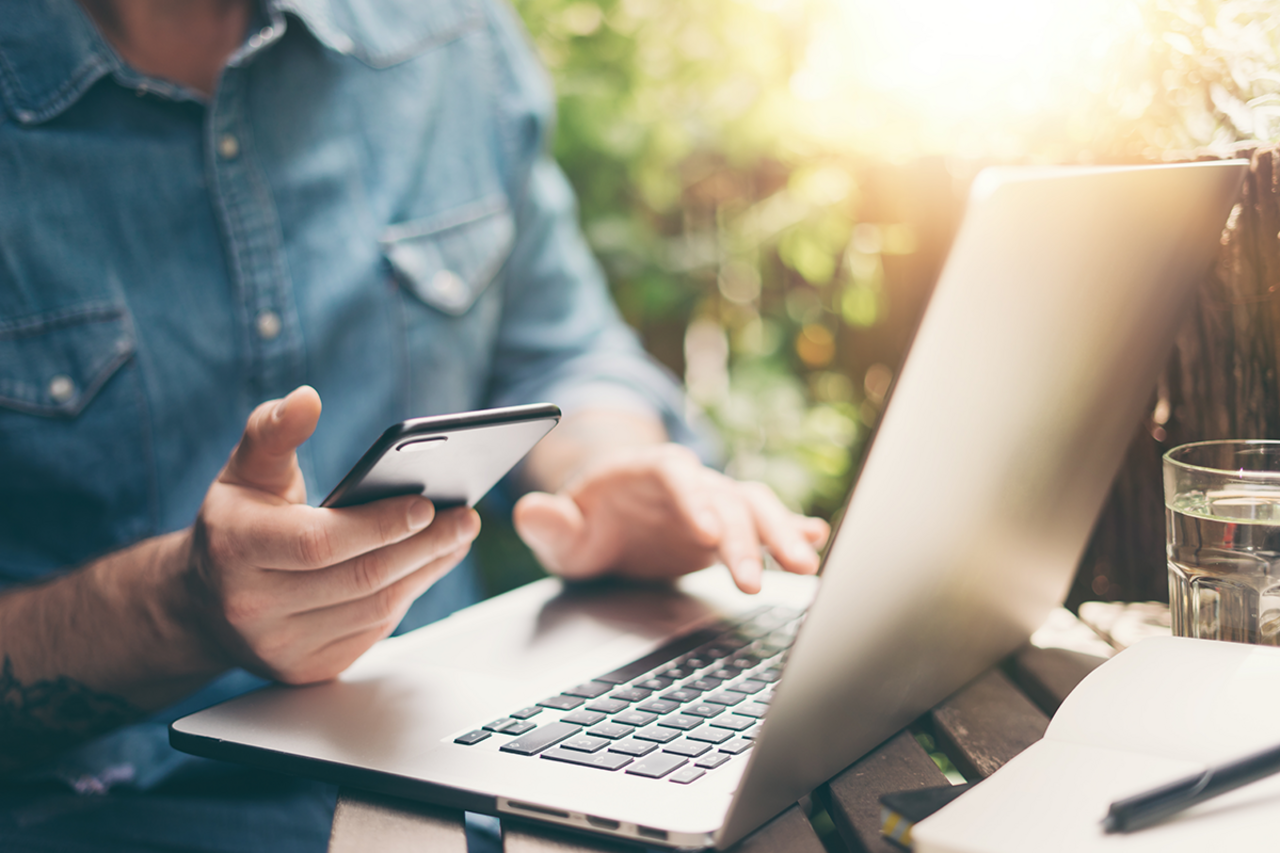 Man working on computer outside, updating OpenScholar website